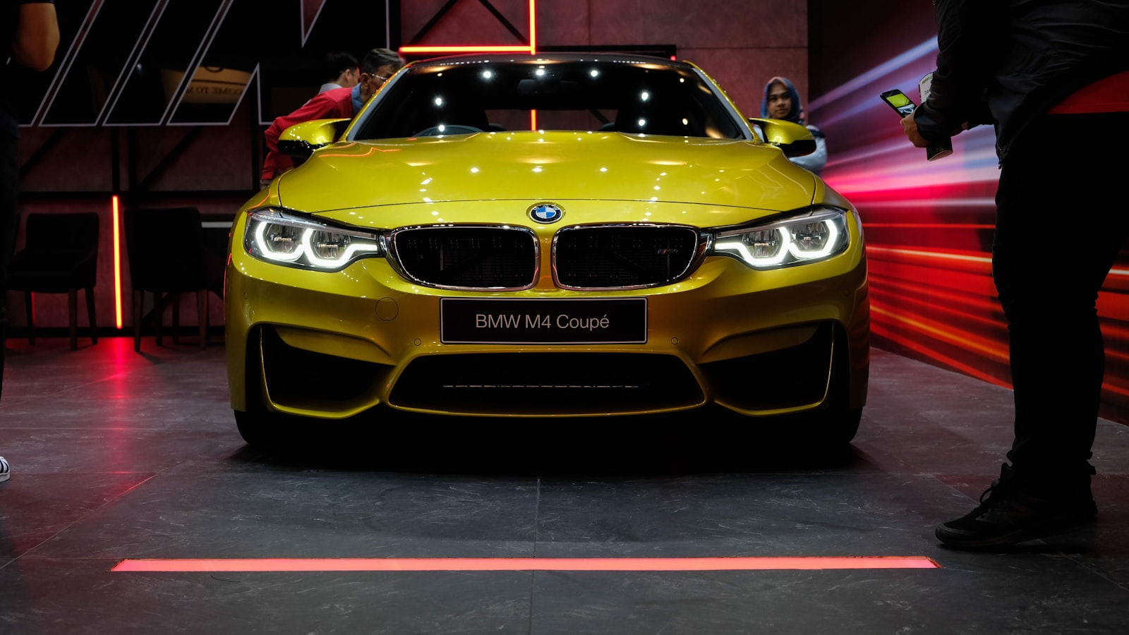 BMW M4 amarillo en exposición — recordatorio de mantenimiento