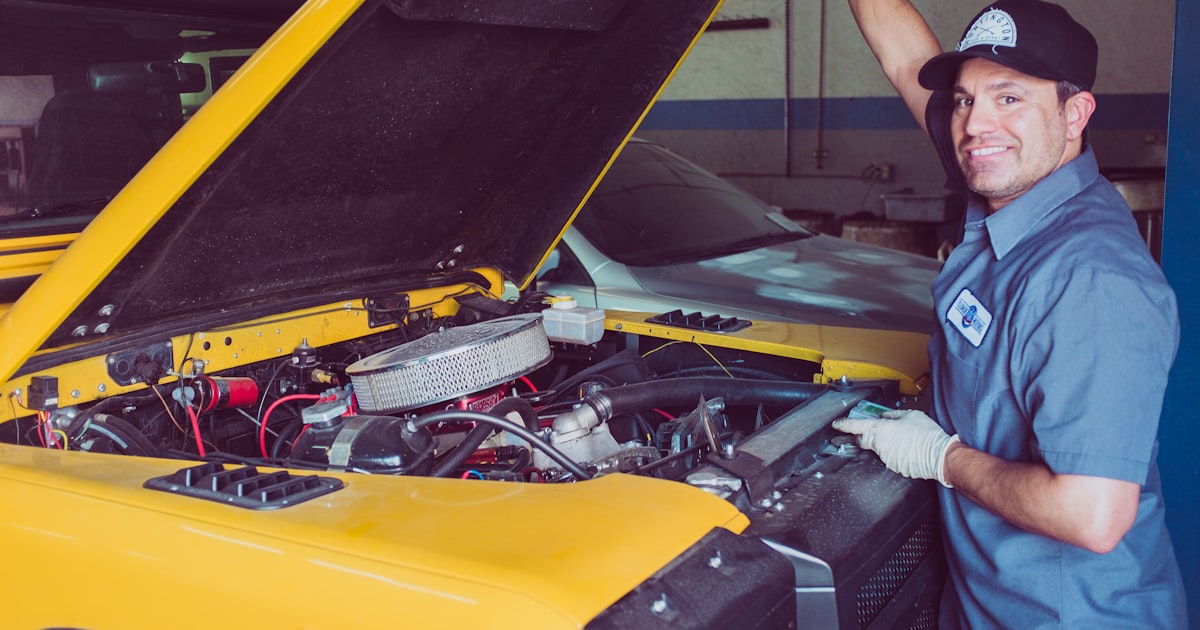 Mecánico realizando reparación bajo el capó de un coche